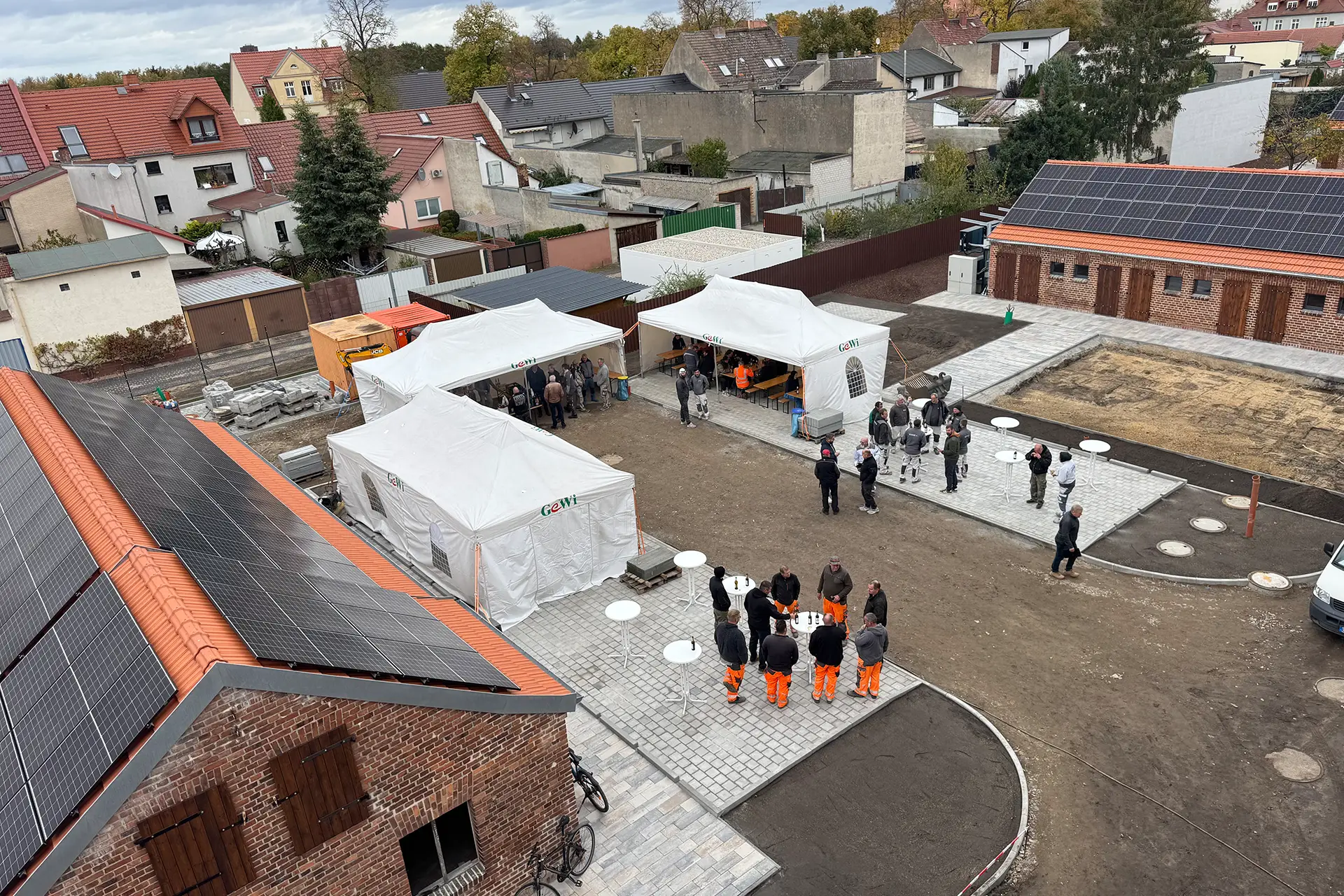 Aufnahme vom Balkon in den Innenhof, in dem das Handwerkergrllen und die Schuppen mit PV-Modulen zu sehen sind.